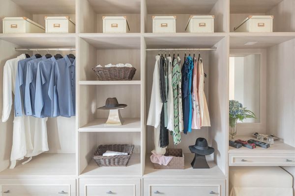 modern wooden wardrobe with clothes hanging on rail in walk in closet